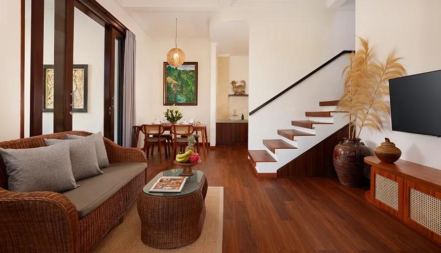 Airy living space featuring a cozy sofa, dining table set, and staircase with wooden accents at Leona Valley View 2BR