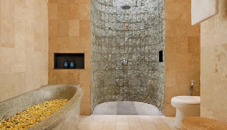 Luxurious master bathroom with a large stone bathtub filled with yellow flowers and a unique stone shower at Leona Valley View 2BR