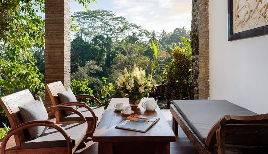 Relaxing villa terrace with wooden chairs, a daybed, and a beautiful view of the lush green forest at Leona Valley View 2BR