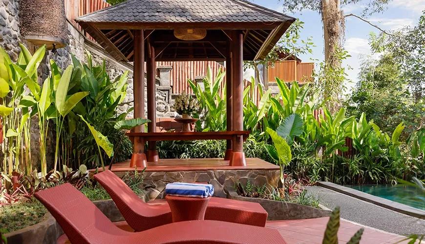 Tropical outdoor sundeck with two red lounge chairs next to a traditional wooden gazebo for relaxing at Leona Valley View 2BR