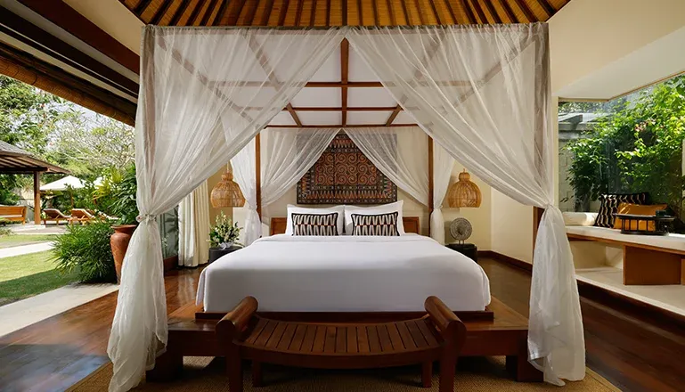 Canopy bed overlooking tropical pool and garden at Nelayan Villa