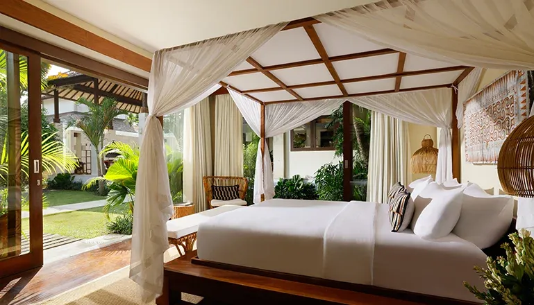 Elegant Bali villa bedroom has draped canopy bed with garden view at Nelayan Villa