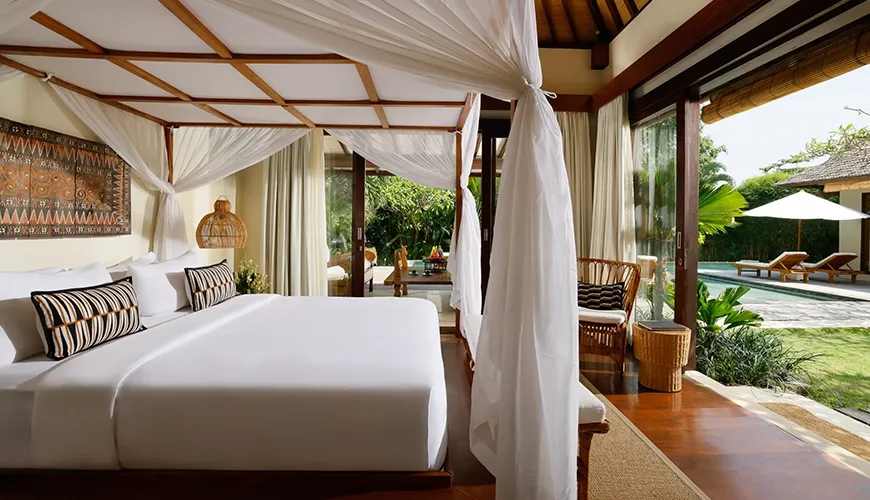 Luxurious villa bedroom with a magnificent four-poster bed and a breathtaking view of the private swimming pool at Nelayan Villa