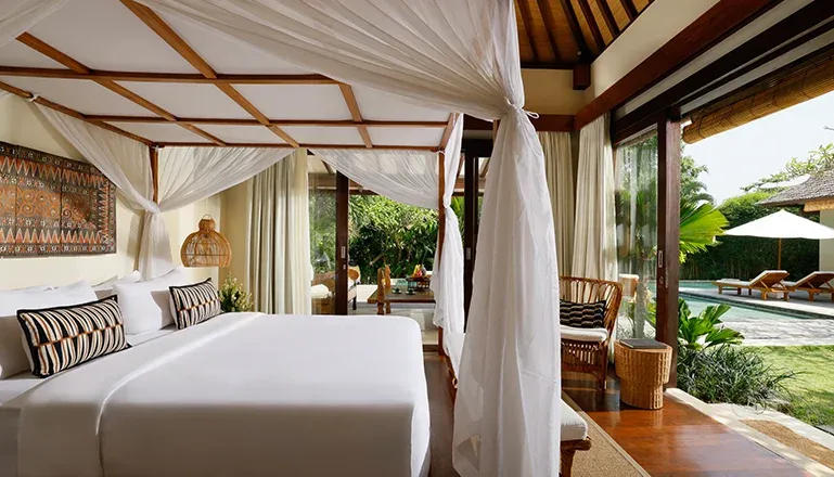 Luxury Bali villa bedroom has canopy bed and pool view at Nelayan Villa