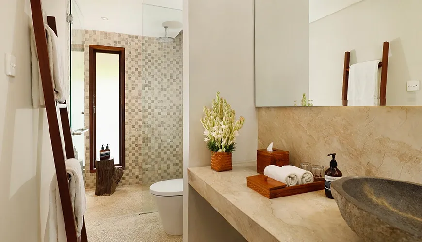 Modern villa bathroom with a unique natural stone basin and a stylish mosaic tiled shower at Nelayan Villa