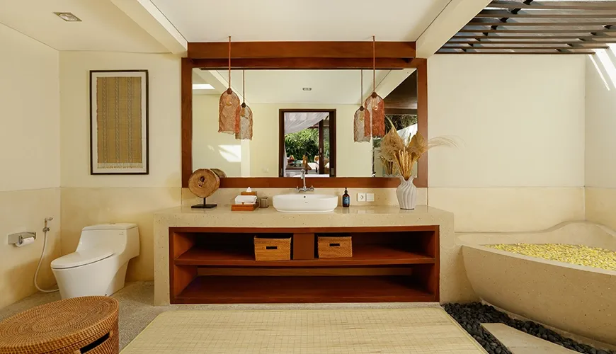 Serene villa bathroom with a unique natural stone bathtub and a stylish wooden vanity with a large mirror at Nelayan Villa
