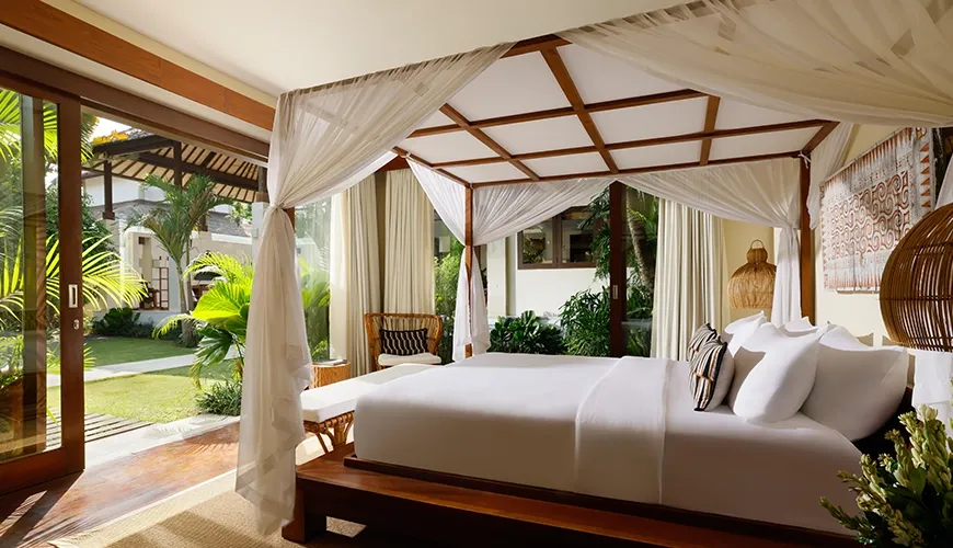 Spacious villa bedroom featuring a romantic canopy bed and stunning views of the lush garden at Nelayan Villa