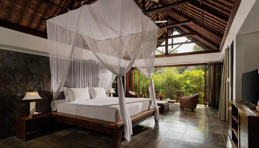 Master bedroom features a romantic bed with net and tropical views at Omecure
