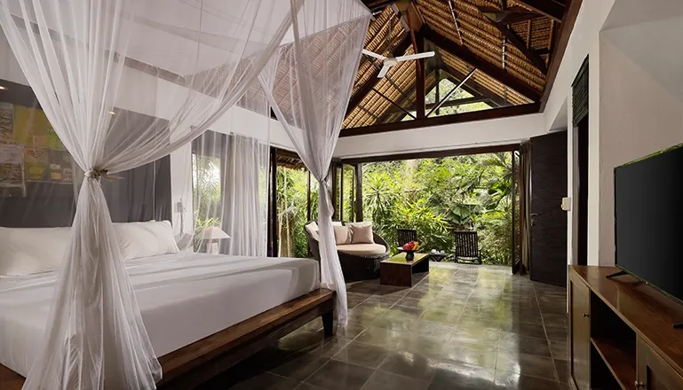 Spacious bedroom features a romantic draped bed and lush tropical views at Omecure