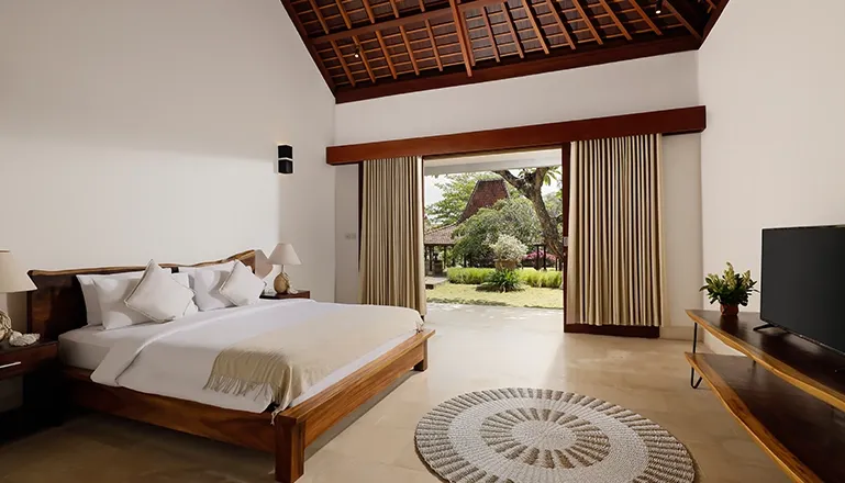 Elegant bedroom with a large bed and dark wood at Omegia Canggu