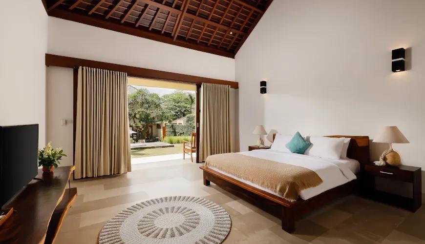 Spacious Balinese bedroom with a vaulted wooden ceiling and an outdoor patio at Omegia Canggu