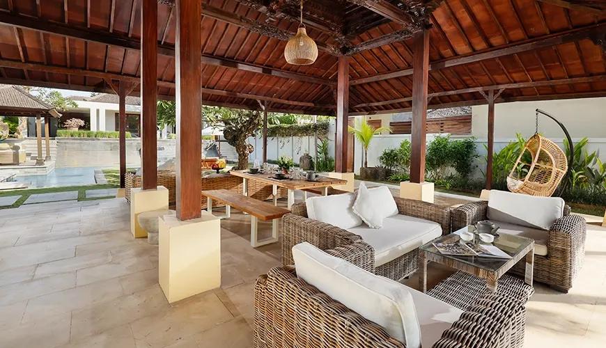 Spacious open-air pavilion with traditional wooden roof, lounge, and dining areas at Omegia Canggu
