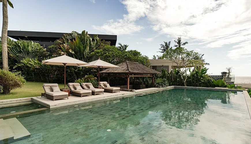 Expansive private villa pool area with comfortable sun loungers, an inviting gazebo, and a beautiful view toward the ocean at Omekai Cemagi