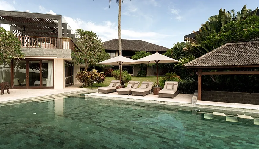 Expansive private villa swimming pool area with luxury sun loungers, resort umbrellas, and a traditional shaded gazebo at Omekai Cemagi