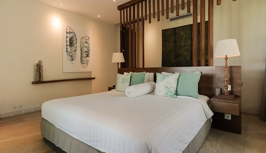 Luxurious villa bedroom featuring a large bed, stylish wooden screen partition, modern lighting, and tropical feather wall art at Omekai Cemagi