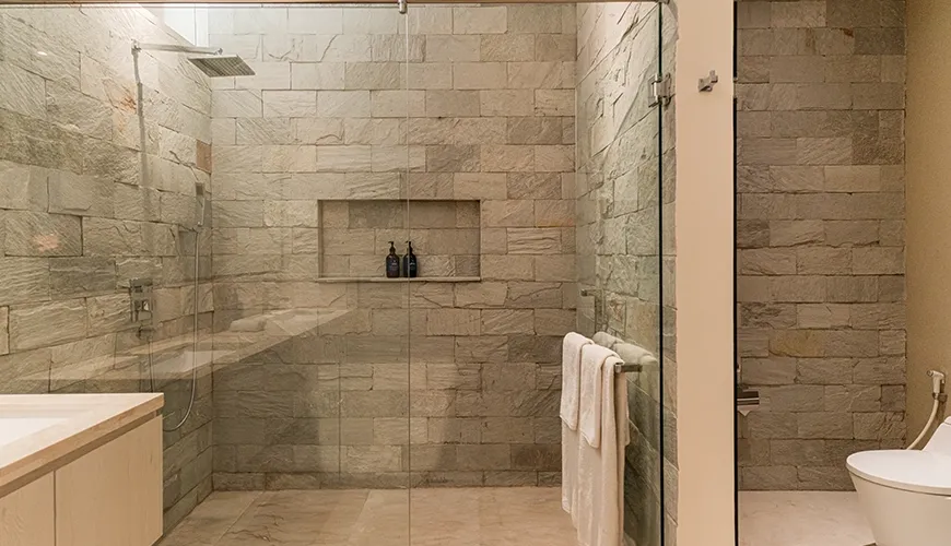 Modern villa bathroom featuring a spacious walk-in shower with beautiful natural stone tiles and elegant glass enclosure for ultimate comfort at Omekai Cemagi