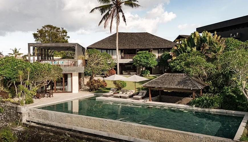 Stunning aerial view of the luxury villa's infinity pool and main house, surrounded by beautiful tropical gardens at Omekai Cemagi