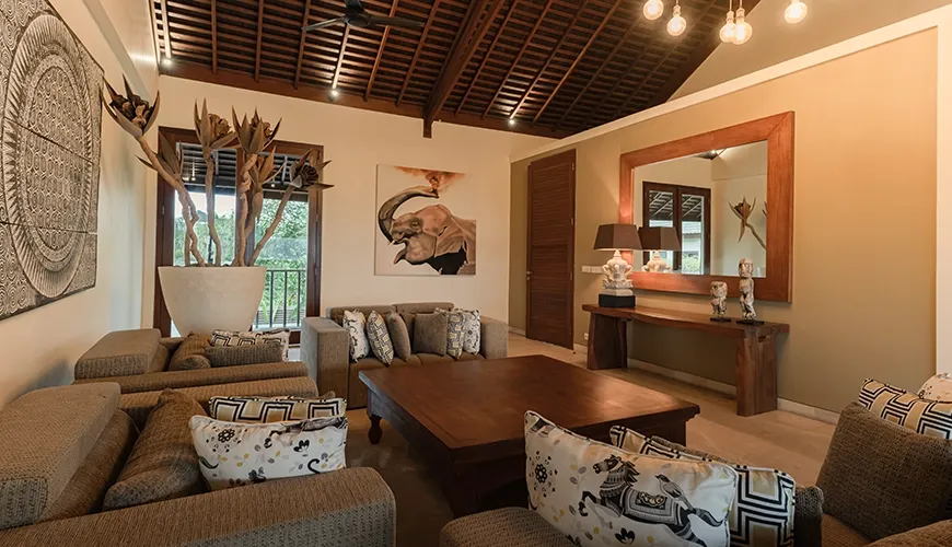 Warm luxury villa living room with a stunning vaulted wooden ceiling, comfortable lounge seating, and bespoke elephant-themed artwork at Omekai Cemagi