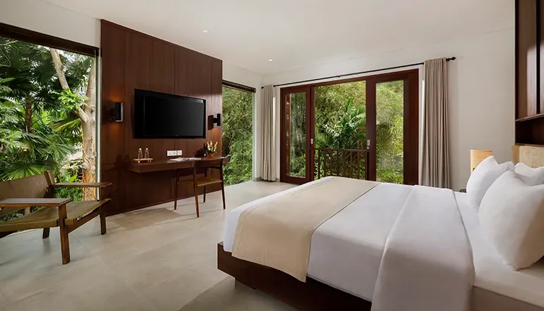 Bedroom with king bed and balcony overlooking lush trees at Omekali