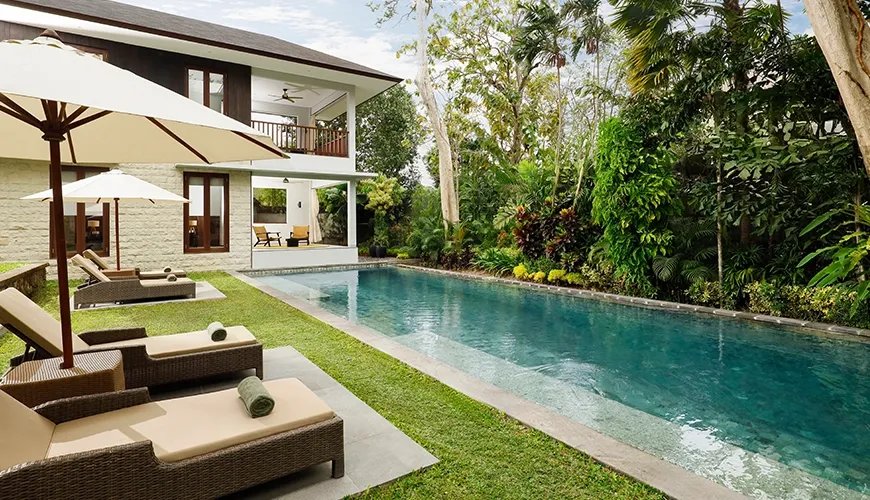Long swimming pool with sun loungers and multi-story villa at Omekali