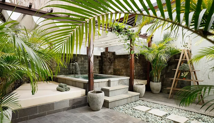 Outdoor jacuzzi with shaded daybed and tropical landscaping at Omekali