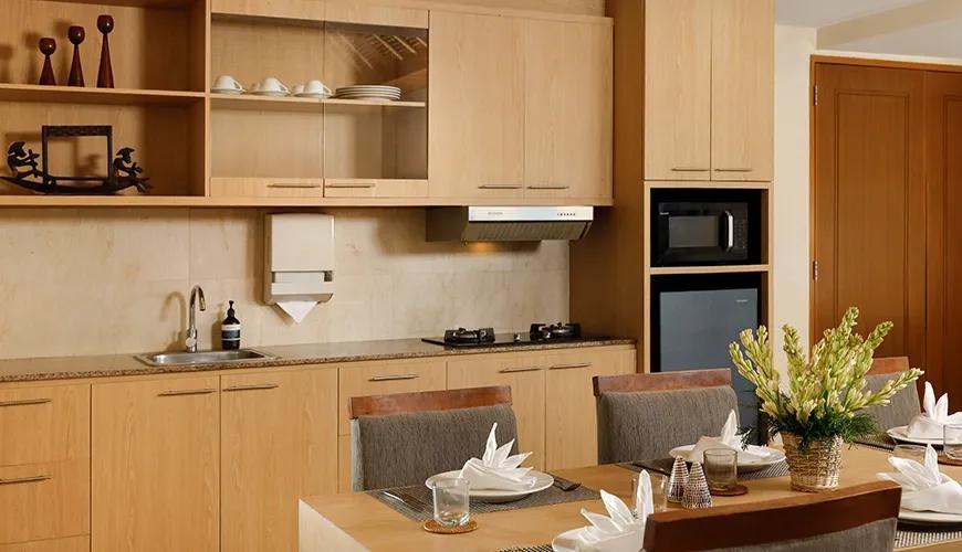 Compact kitchen dining area wooden cabinets appliances table place settings at Sara Residence