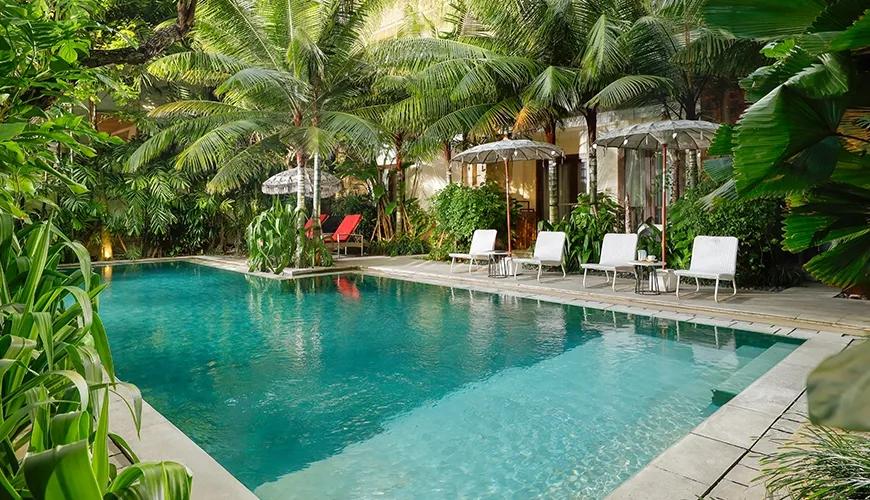 Lush tropical pool area traditional umbrellas white sun loungers vibrant greenery at Sara Residence