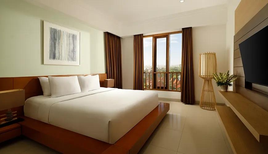 Spacious bedroom white bed wooden frame large window city view at Sara Residence