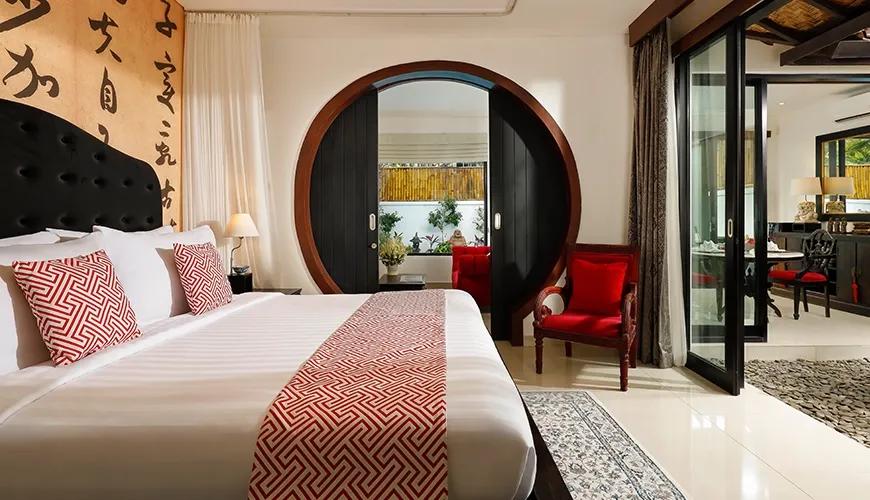 Elegant master bedroom featuring a king-size bed, ornate furniture, and a round wooden doorway with an Asian-inspired theme at Shanti Estate 1BR