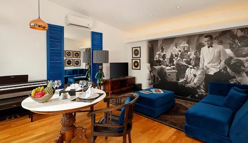 Modern villa living room featuring a comfortable blue velvet sofa, a round dining table, and a large black and white mural at Shanti Estate 1BR