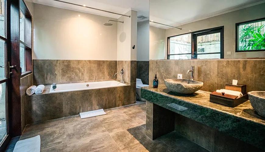 Elegant Balinese-style bathroom with a large bathtub and unique stone washbasins at shanti estate