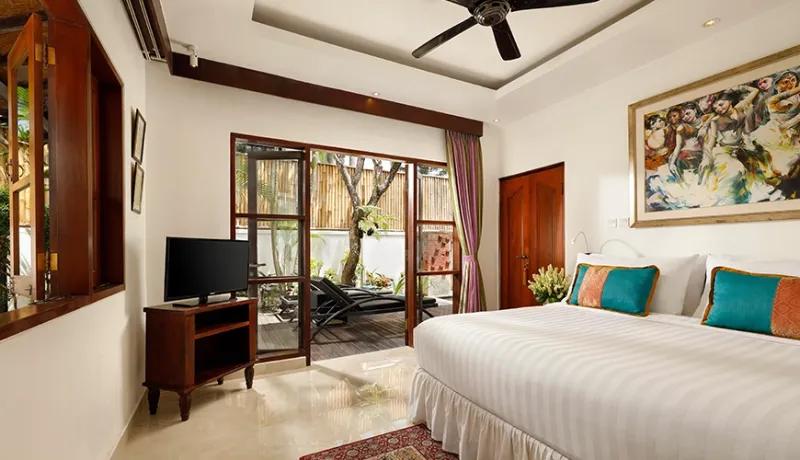 Elegant bedroom interior with warm wood furniture and large glass doors leading to a private terrace at Shanti Estate