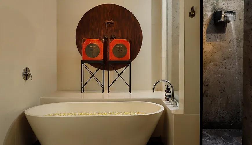 Elegant master bathroom featuring a white soaking tub filled with flower petals and stone water feature at Shanti Estate