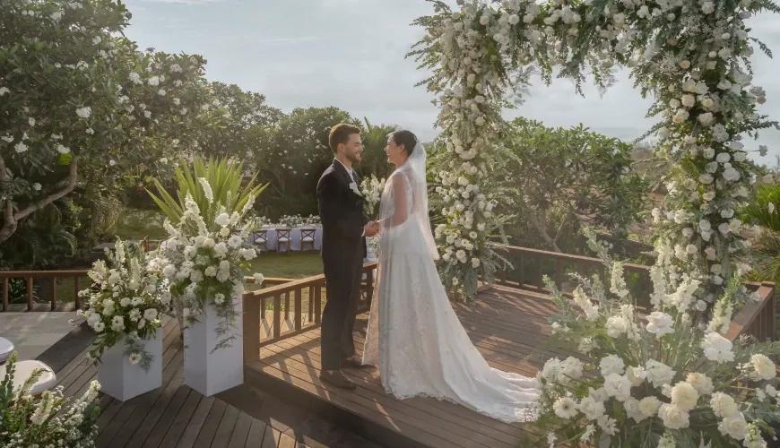 Elegant outdoor wedding venue on a wooden deck with white floral arches overlooking a tropical garden at Shanti Residence