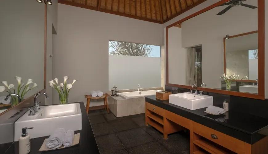 Elegant villa bathroom featuring double vanity sinks and a square soaking tub under a high vaulted ceiling at Shanti Residence