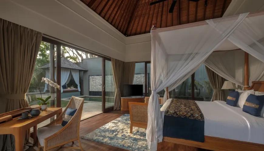 Elegant villa bedroom with a canopy bed and large glass doors opening to a private pool area at Shanti Residence