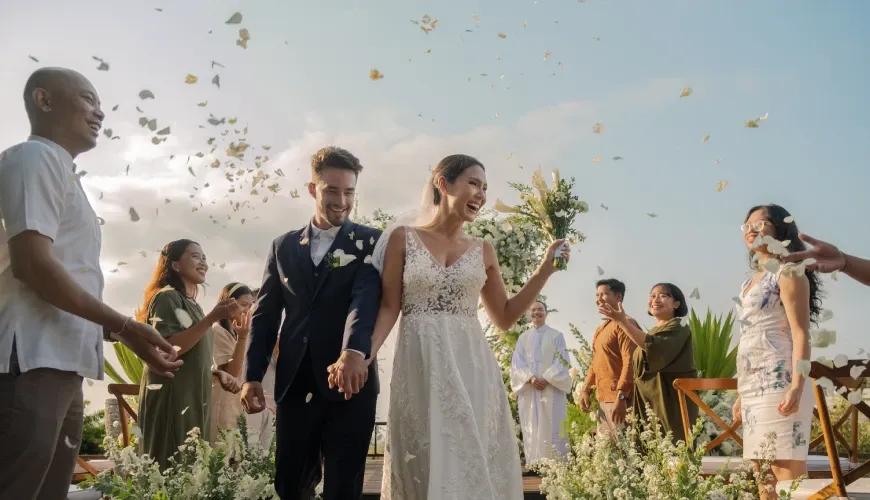 Happy bride and groom walking through flower petal toss during a beautiful outdoor villa wedding ceremony at Shanti Residence