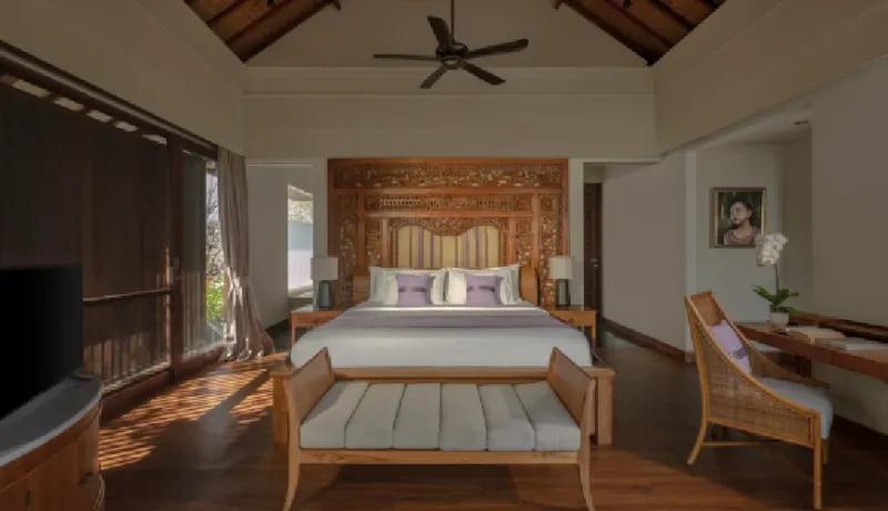 Luxurious villa bedroom featuring an ornate wooden headboard and sliding glass doors leading to a balcony at Shanti Residence