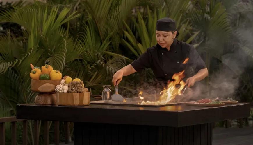 Professional villa chef preparing a gourmet barbecue dinner on an outdoor grill during a tropical sunset at Shanti Residence