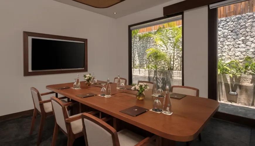 Professional villa meeting room featuring a wooden conference table and wall-mounted television with a garden view at Shanti Residence
