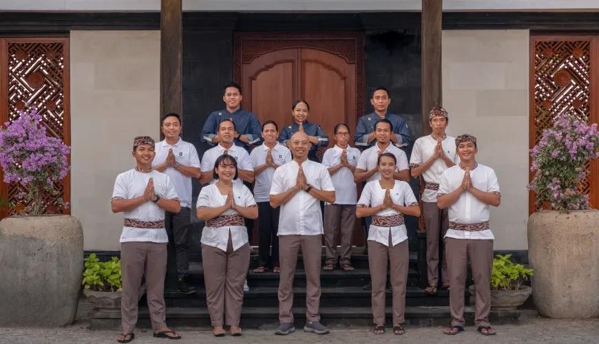 Professional villa staff members in traditional uniforms smiling and greeting guests at a luxury tropical estate at Shanti Residence