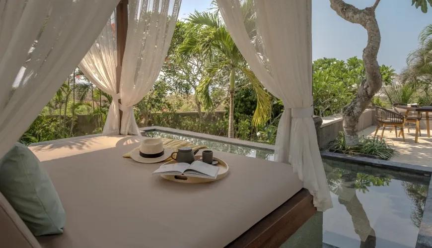 Relaxing outdoor gazebo with a daybed and tea set overlooking a private pool and tropical garden at Shanti Residence