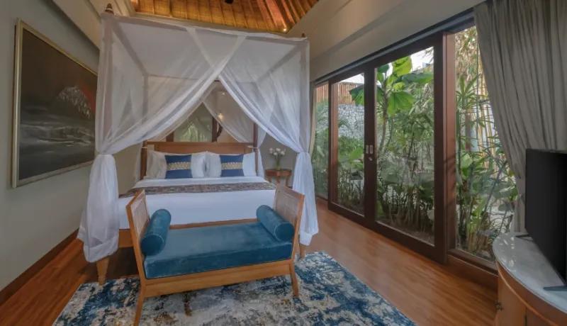 Spacious villa bedroom with a king-sized bed and sliding glass doors revealing a lush garden at Shanti Residence