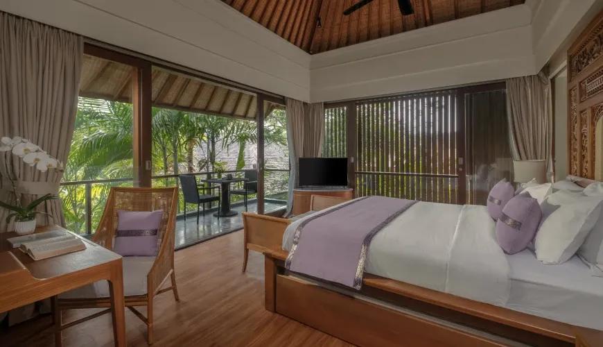 Tropical villa bedroom featuring purple accents and a private balcony overlooking lush palm trees and greenery at Shanti Residence