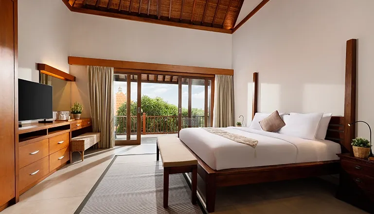 Bright bedroom features a large bed and balcony overlooking green scenery at The Bija Villas