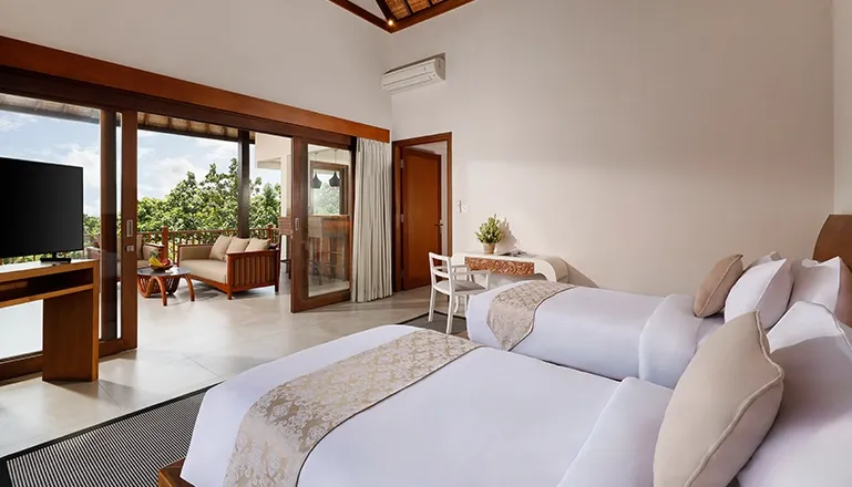 Bright bedroom features two single beds and balcony overlooking lush greenery at The Bija Villas