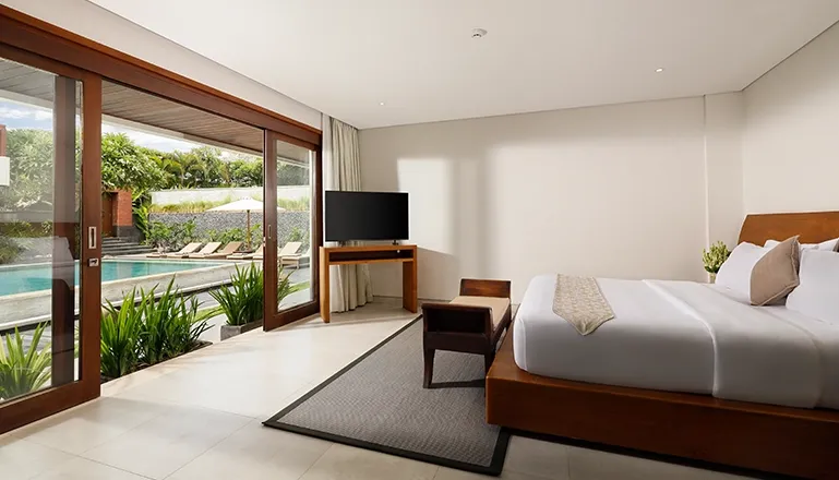 Contemporary bedroom includes a large bed and opens to the pool area at The Bija Villas