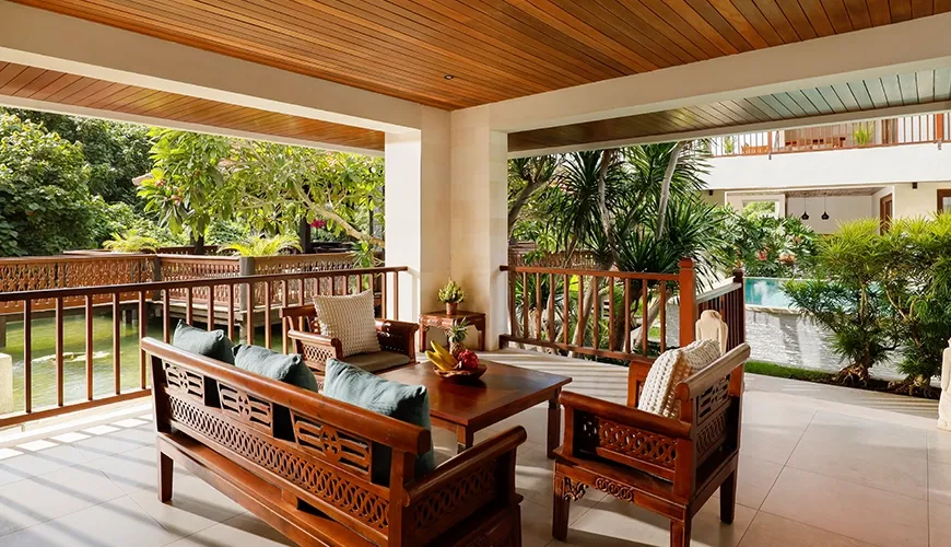 Covered outdoor living area with traditional wooden furniture, water feature, and lush views at The Bijas Villas