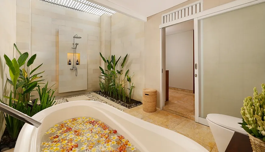 Luxurious outdoor bathroom with freestanding bathtub, flower petals, and rain shower at The Bija Villas