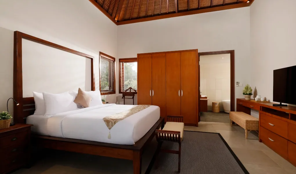 Modern bedroom with traditional wooden furniture and high ceilings at The Bija Villas